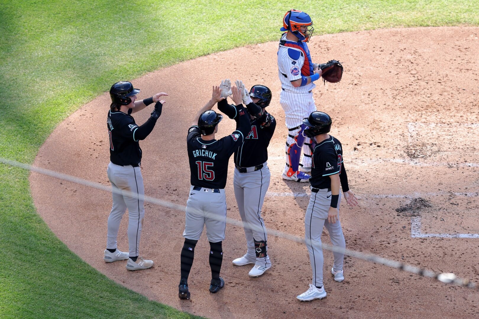 Jake McCarthy, Kevin Newman, and Randal Grichuk celebrate with Christian Walker, whose grand slam put the Diamondbacks up 4-0 over the Mets.