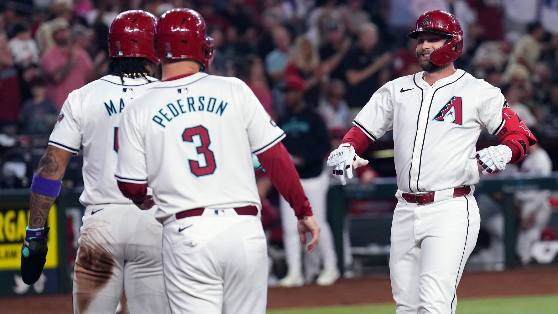 Diamondbacks first baseman Christian Walker celebrates at home plate with Ketel Marte and Joc Pederson after hitting a three-run home run.