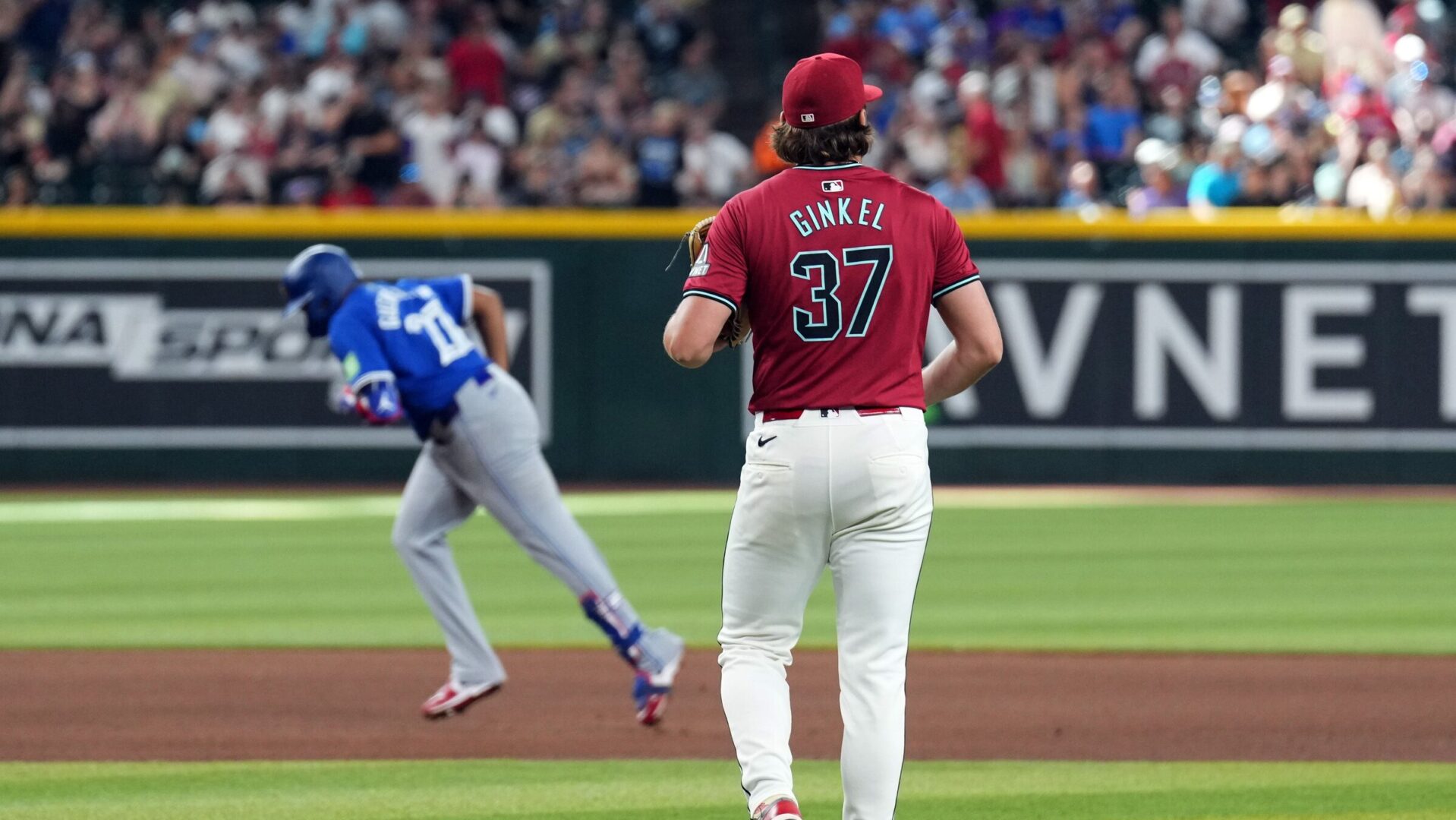 Arizona Diamondbacks pitcher Kevin Ginkel watches Vladimir Guerrero Jr. round the bases after allowing a go-ahead home run.