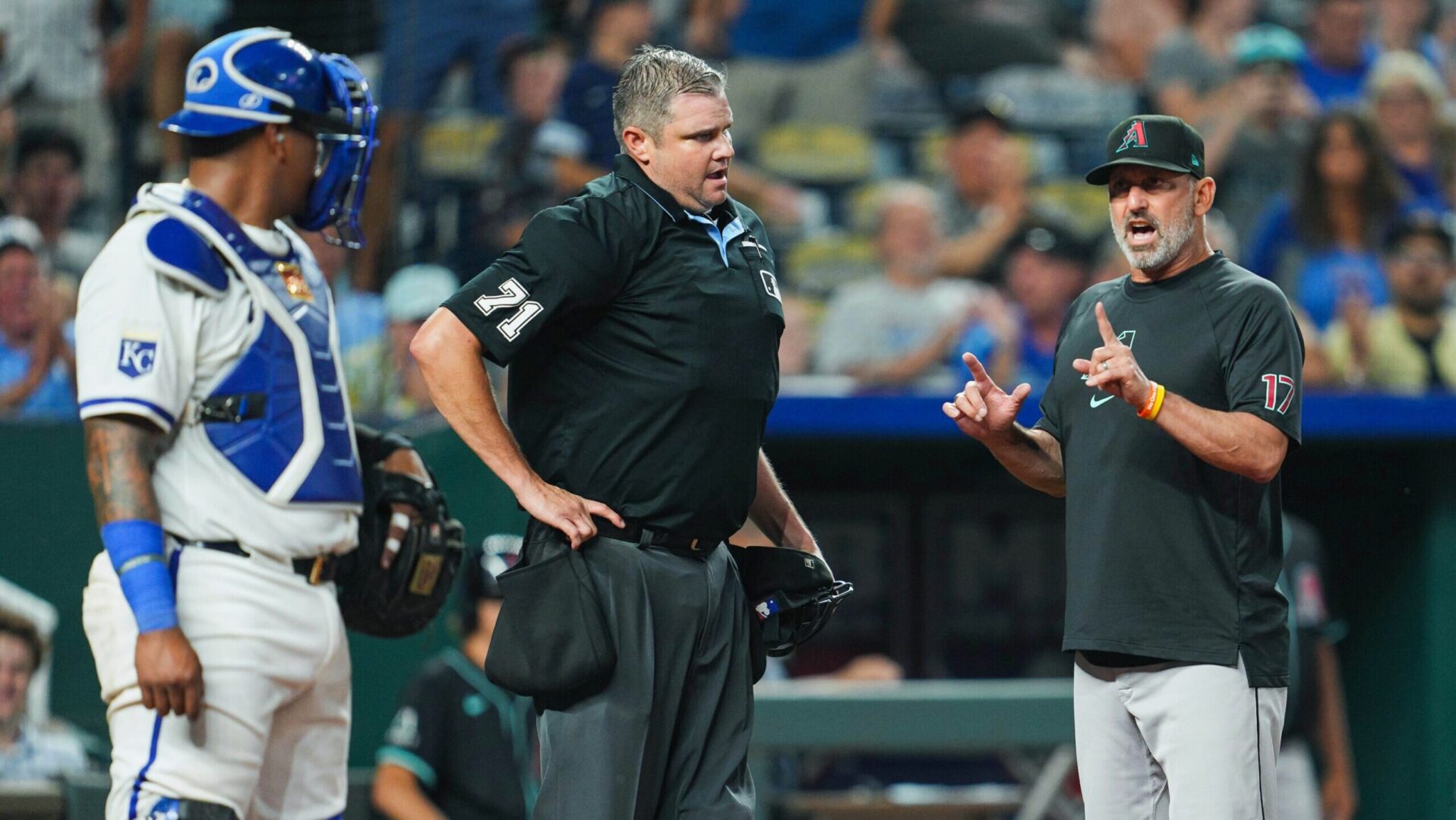 Diamondbacks manager Torey Lovullo argues with home plate umpire Jordan Baker, with Royals catcher Salvador Perez listening in.