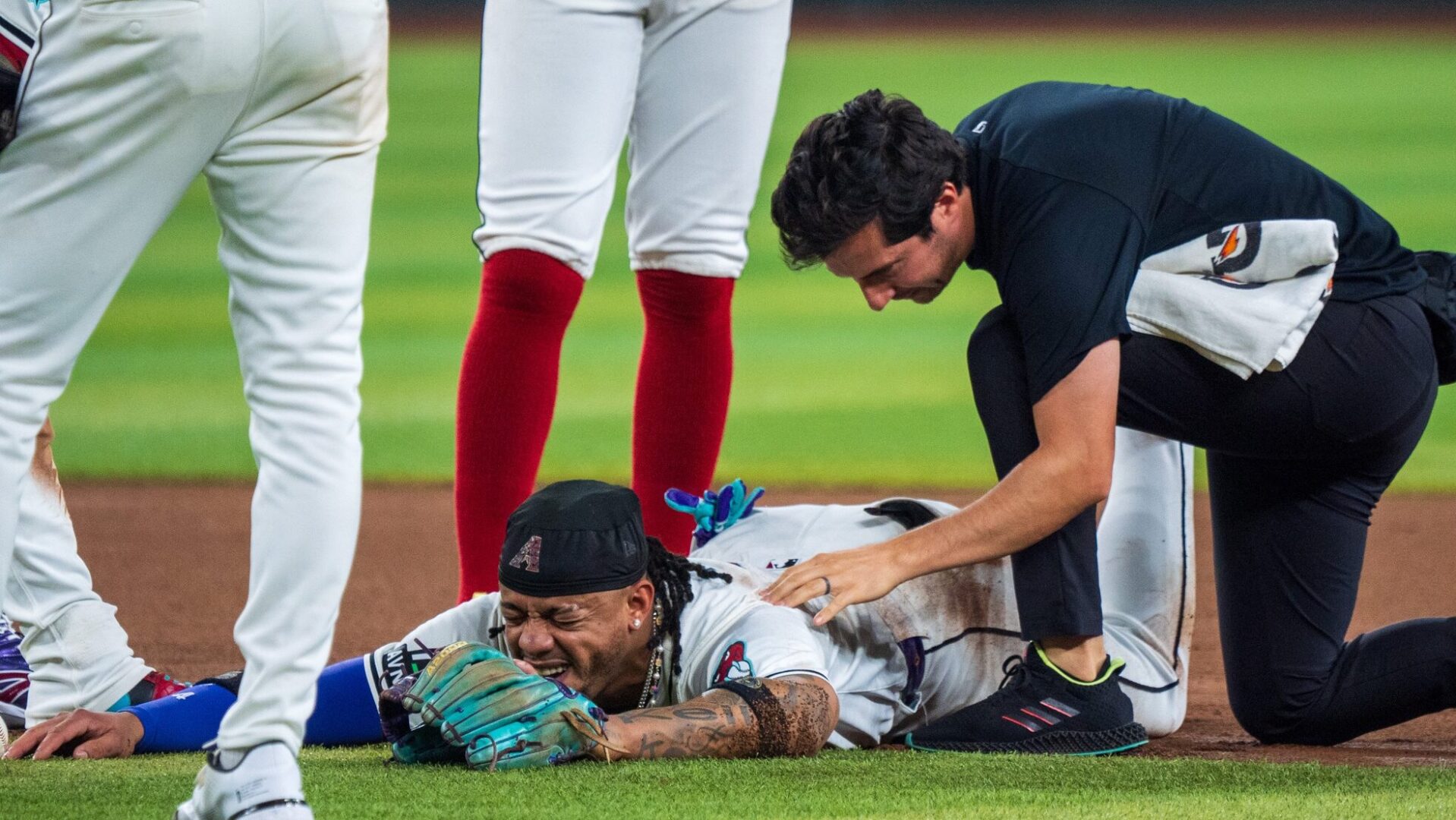 Ketel Marte lays prone on the ground while being examined by trainer Max Esposito.