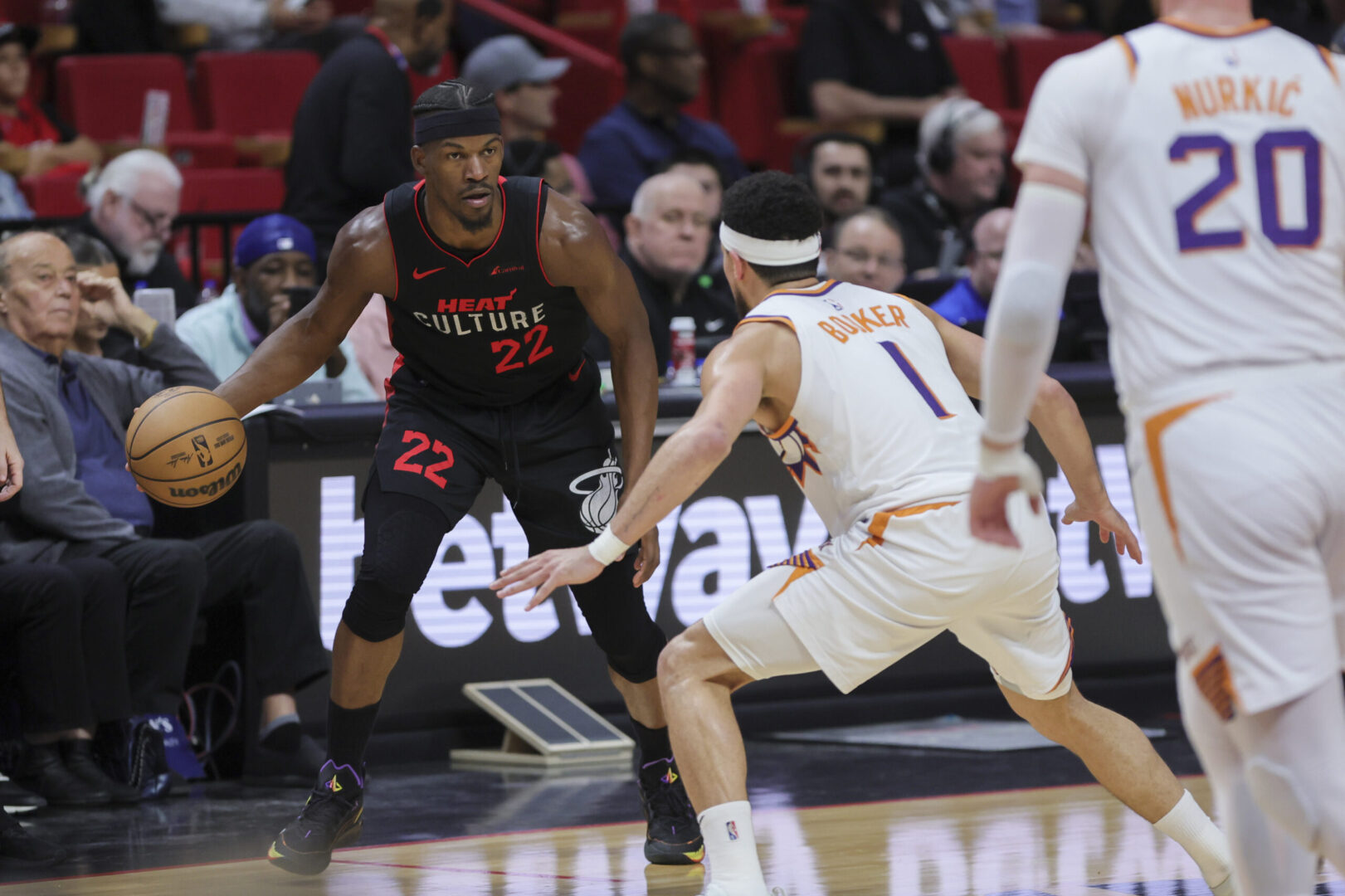 Jan 29, 2024; Miami, Florida, USA; Miami Heat forward Jimmy Butler (22) dribbles the basketball as Phoenix Suns guard Devin Booker (1) defends during the third quarter at Kaseya Center. Mandatory Credit: Sam Navarro-Imagn Images