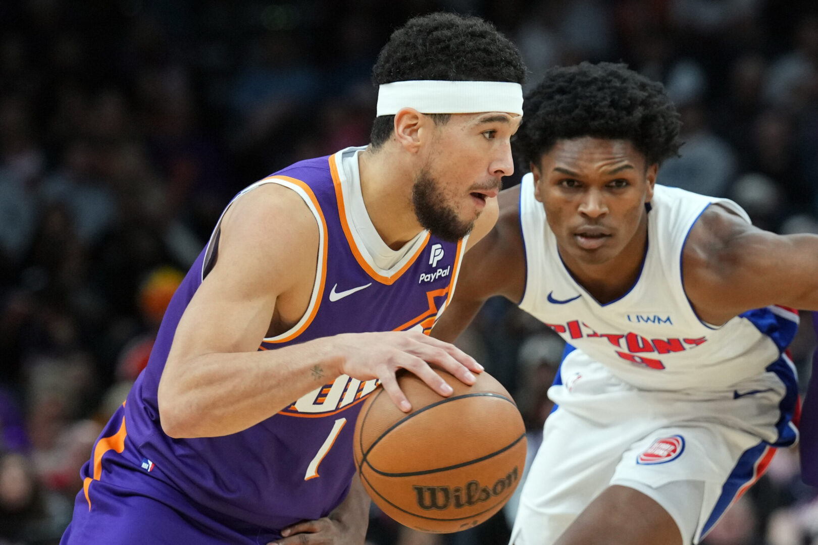 Feb 14, 2024; Phoenix, Arizona, USA; Phoenix Suns guard Devin Booker (1) dribbles by Detroit Pistons forward Ausar Thompson (9) during the first half at Footprint Center. Mandatory Credit: Joe Camporeale-Imagn Images