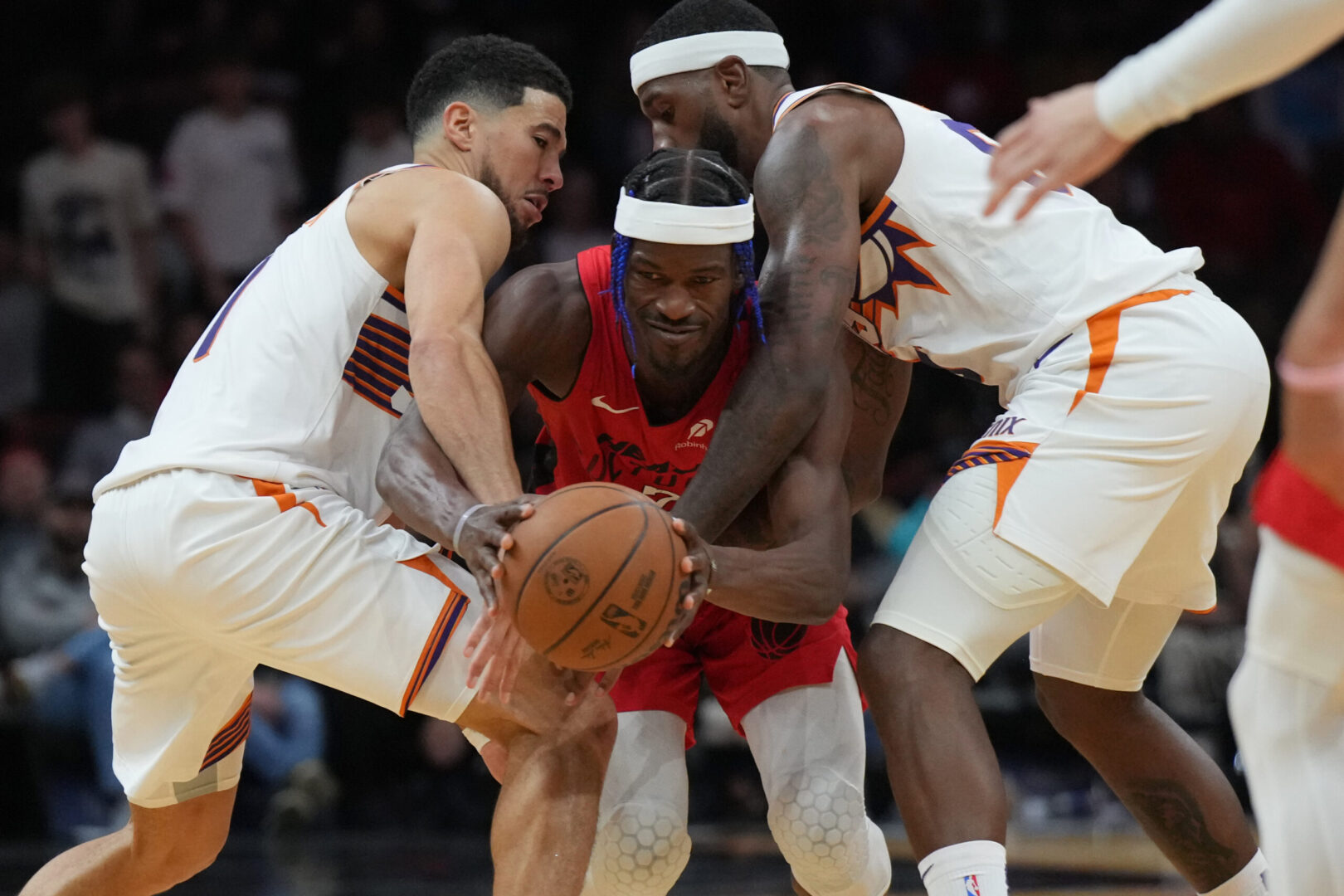 Dec 7, 2024; Miami, Florida, USA; Miami Heat forward Jimmy Butler (22) tries to drive between Phoenix Suns guard Devin Booker (left) and forward Royce O'Neale (right) during the second half at Kaseya Center. Mandatory Credit: Jim Rassol-Imagn Images