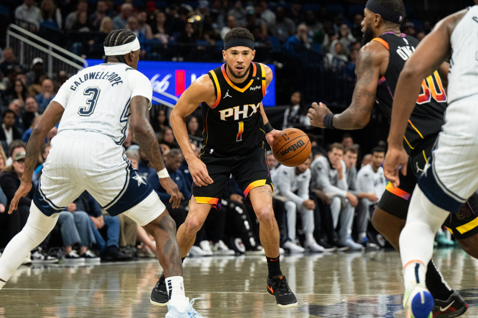 Dec 8, 2024; Orlando, Florida, USA; Phoenix Suns guard Devin Booker (1) dribbles the ball against Orlando Magic guard Kentavious Caldwell-Pope (3) in the third quarter at Kia Center. Mandatory Credit: Jeremy Reper-Imagn Images