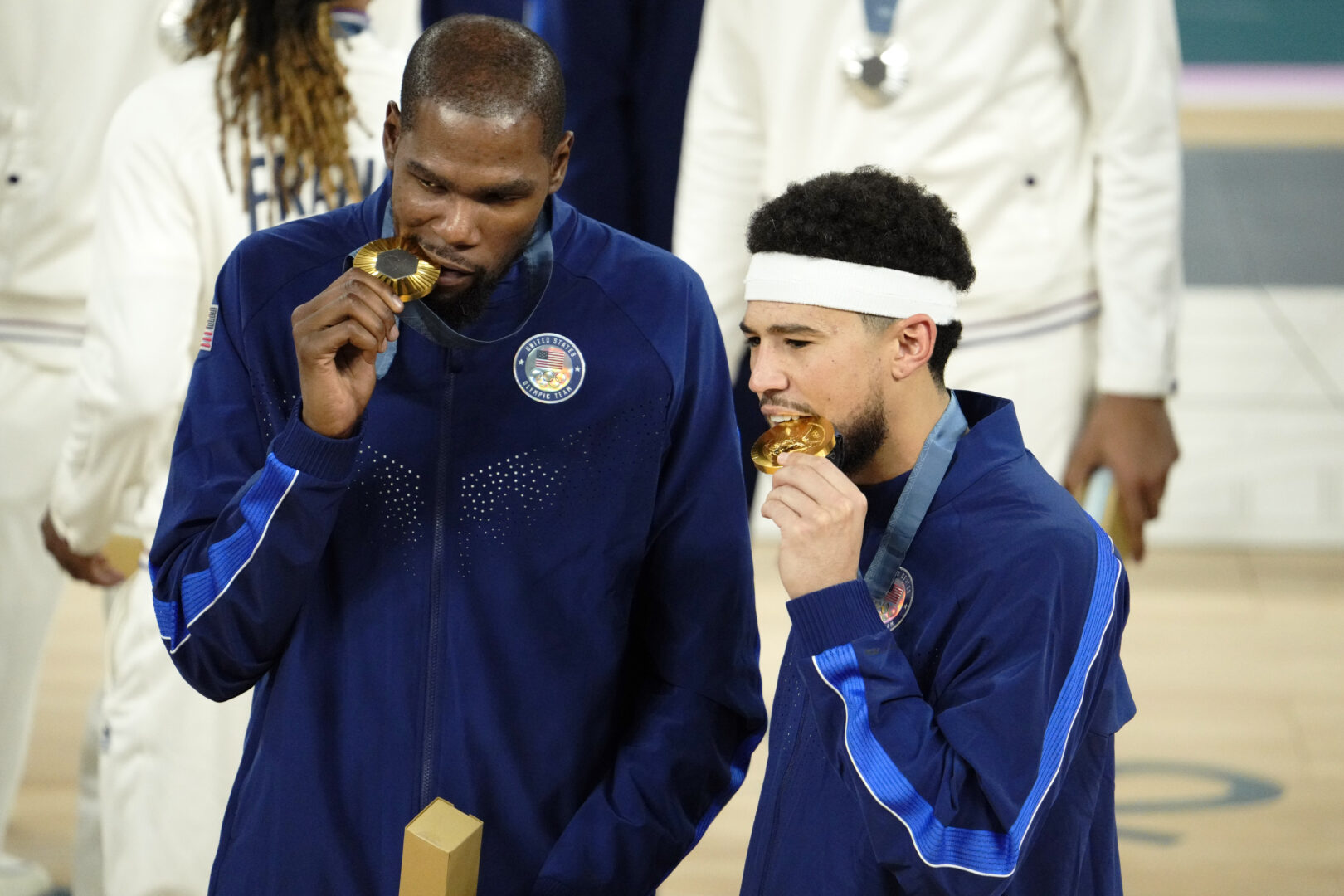 Aug 10, 2024; Paris, France; United States guard Kevin Durant (7) and guard Devin Booker (15) celebrate with their gold medals on the podium after defeating France in the men's basketball gold medal game during the Paris 2024 Olympic Summer Games at Accor Arena. Mandatory Credit: Rob Schumacher-Imagn Images