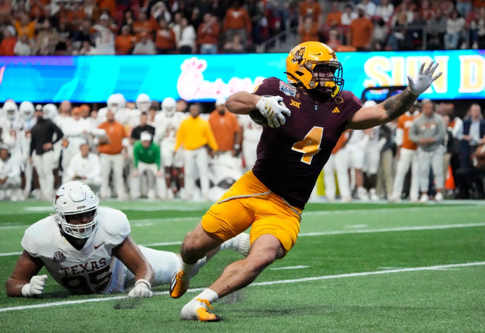 Arizona State running back Cam Skattebo (4) escapes a tackle by Texas defensive lineman Alfred Collins (95) during the fourth quarter in the Chick-fil-A Peach Bowl in Atlanta on Wednesday, Jan. 1, 2025.