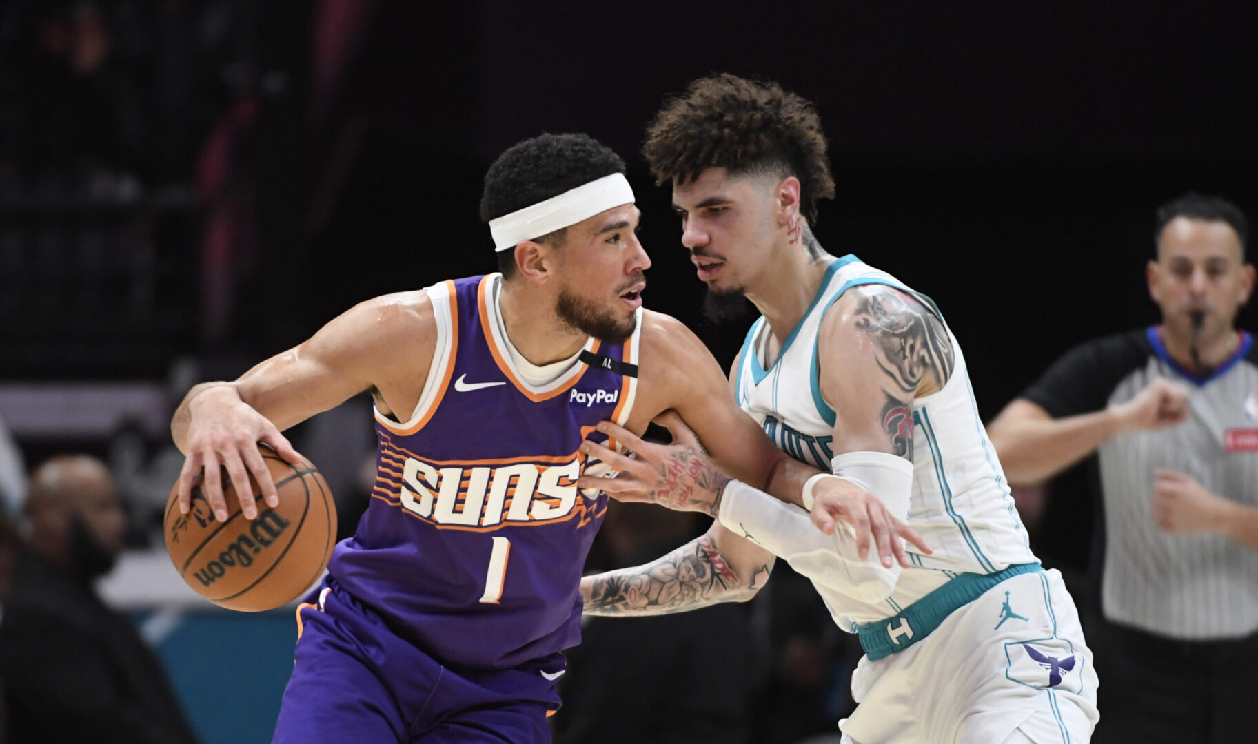 Jan 7, 2025; Charlotte, North Carolina, USA; Phoenix Suns guard Devin Booker (1) drives past Charlotte Hornets guard LaMelo Ball (1) during the first half at the Spectrum Center. Mandatory Credit: Sam Sharpe-Imagn Images