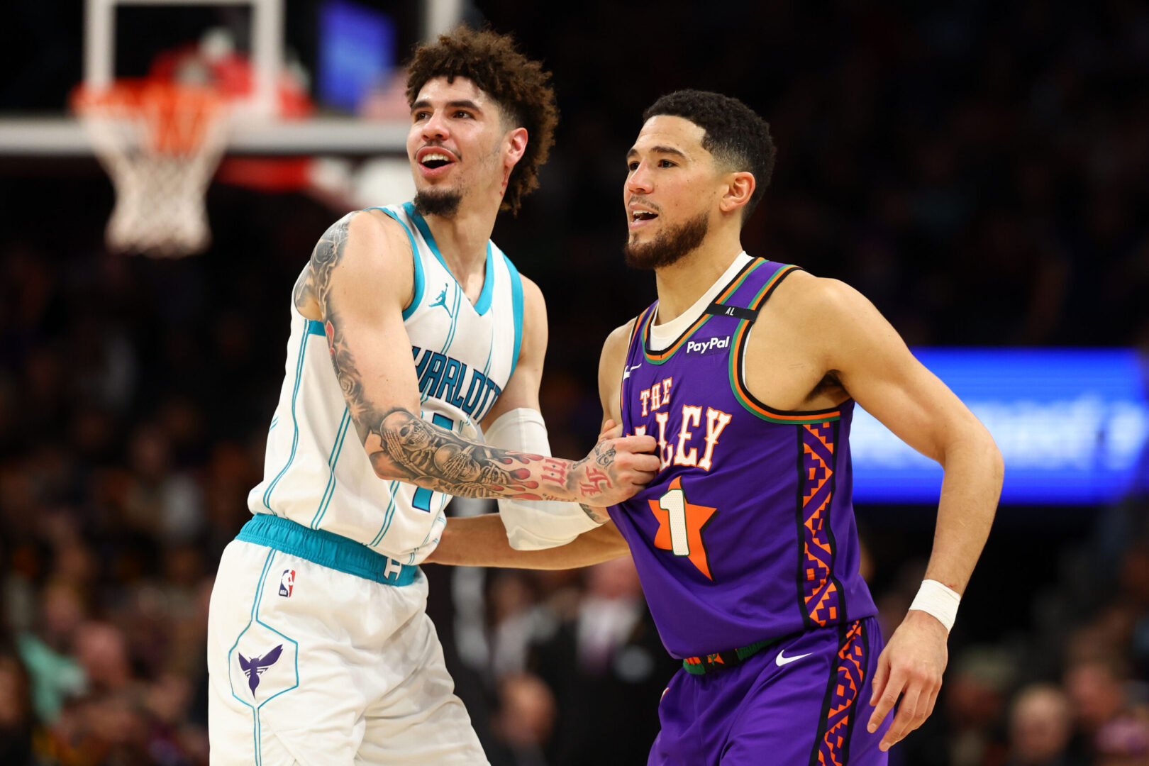 Jan 12, 2025; Phoenix, Arizona, USA; Charlotte Hornets guard LaMelo Ball (1) reacts with Phoenix Suns guard Devin Booker (1) during the first half at Footprint Center. Mandatory Credit: Mark J. Rebilas-Imagn Images