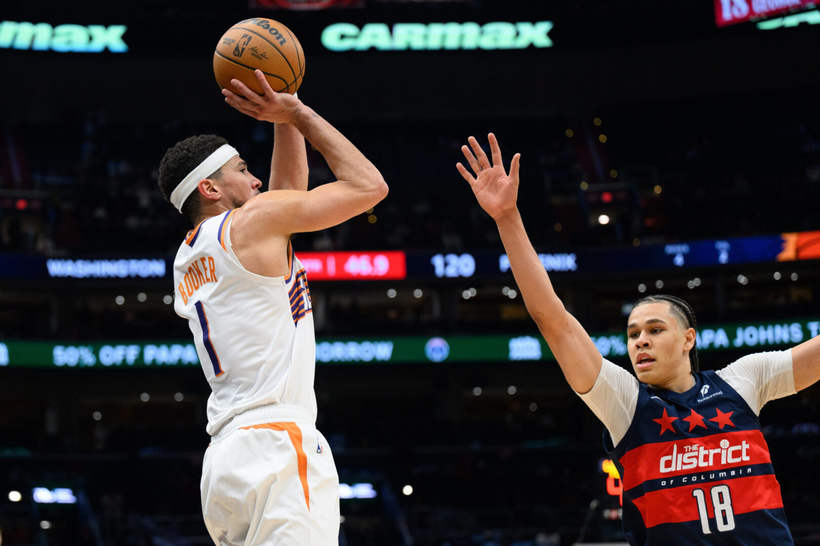 Jan 16, 2025; Washington, District of Columbia, USA; Phoenix Suns guard Devin Booker (1) shoots a three point shot against Washington Wizards forward Kyshawn George (18) during the fourth quarter at Capital One Arena. Mandatory Credit: Reggie Hildred-Imagn Images