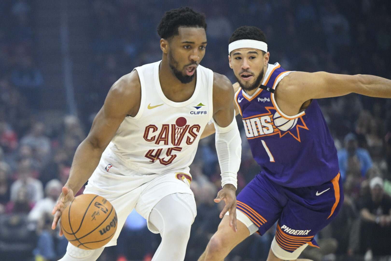 Jan 20, 2025; Cleveland, Ohio, USA; Cleveland Cavaliers guard Donovan Mitchell (45) dribbles beside Phoenix Suns guard Devin Booker (1) in the first quarter at Rocket Mortgage FieldHouse. Mandatory Credit: David Richard-Imagn Images