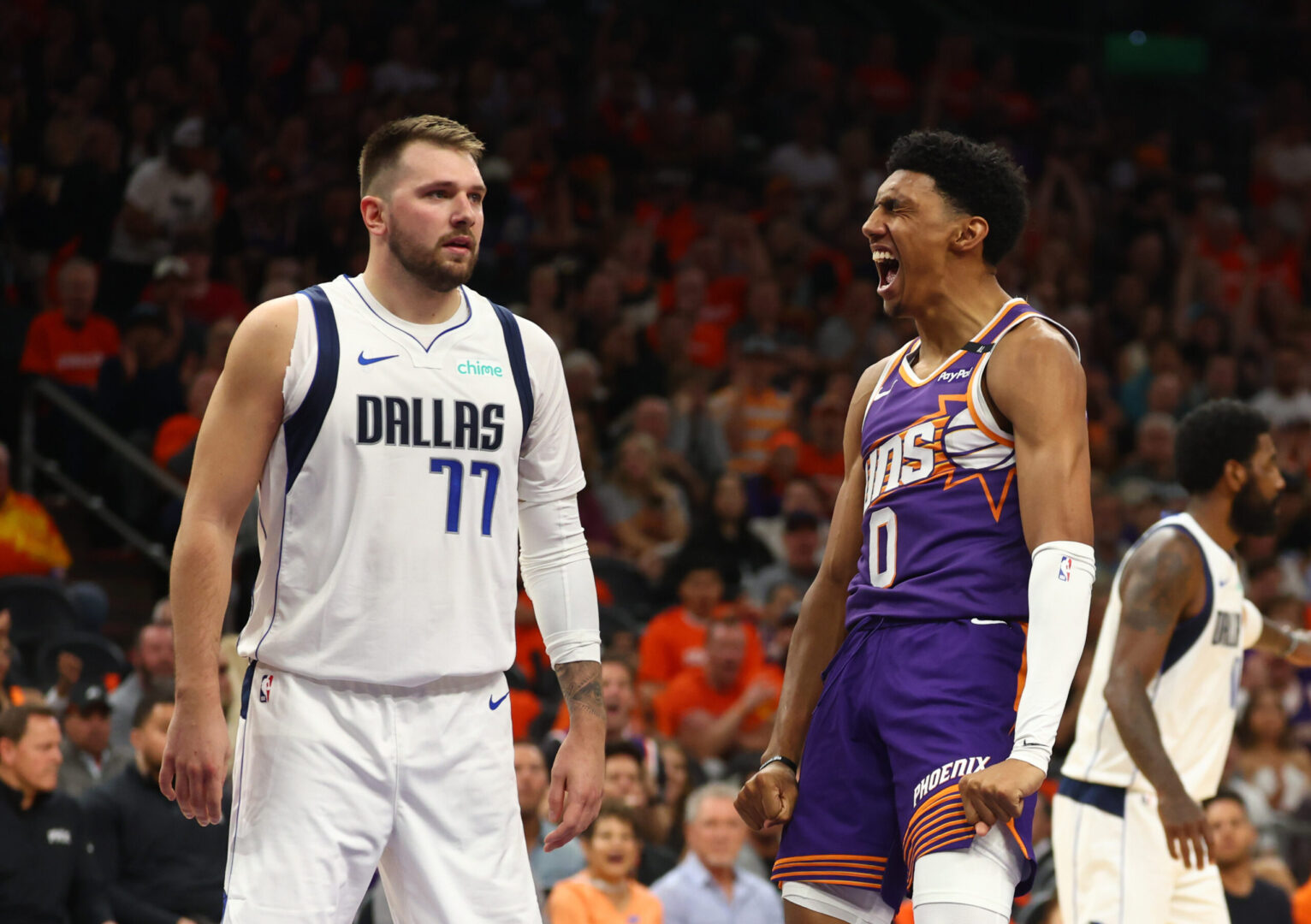 Oct 26, 2024; Phoenix, Arizona, USA; Phoenix Suns forward Ryan Dunn (0) celebrates a dunk against Dallas Mavericks guard Luka Doncic (77) in the first half of the home opener at Footprint Center. Mandatory Credit: Mark J. Rebilas-Imagn Images
