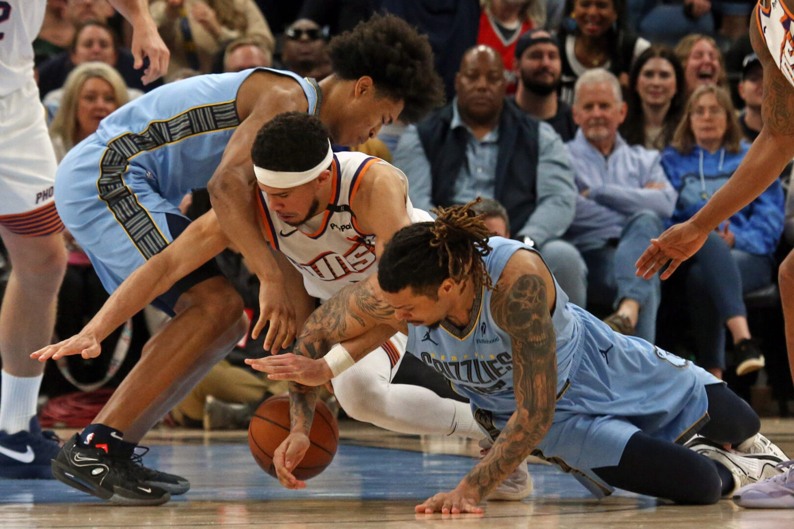 Feb 25, 2025; Memphis, Tennessee, USA; Memphis Grizzlies forward Jaylen Wells (left), forward Brandon Clarke (right) and Phoenix Suns guard Devin Booker (middle) battle for a loose ball during the fourth quarter at FedExForum. Mandatory Credit: Petre Thomas-Imagn Images