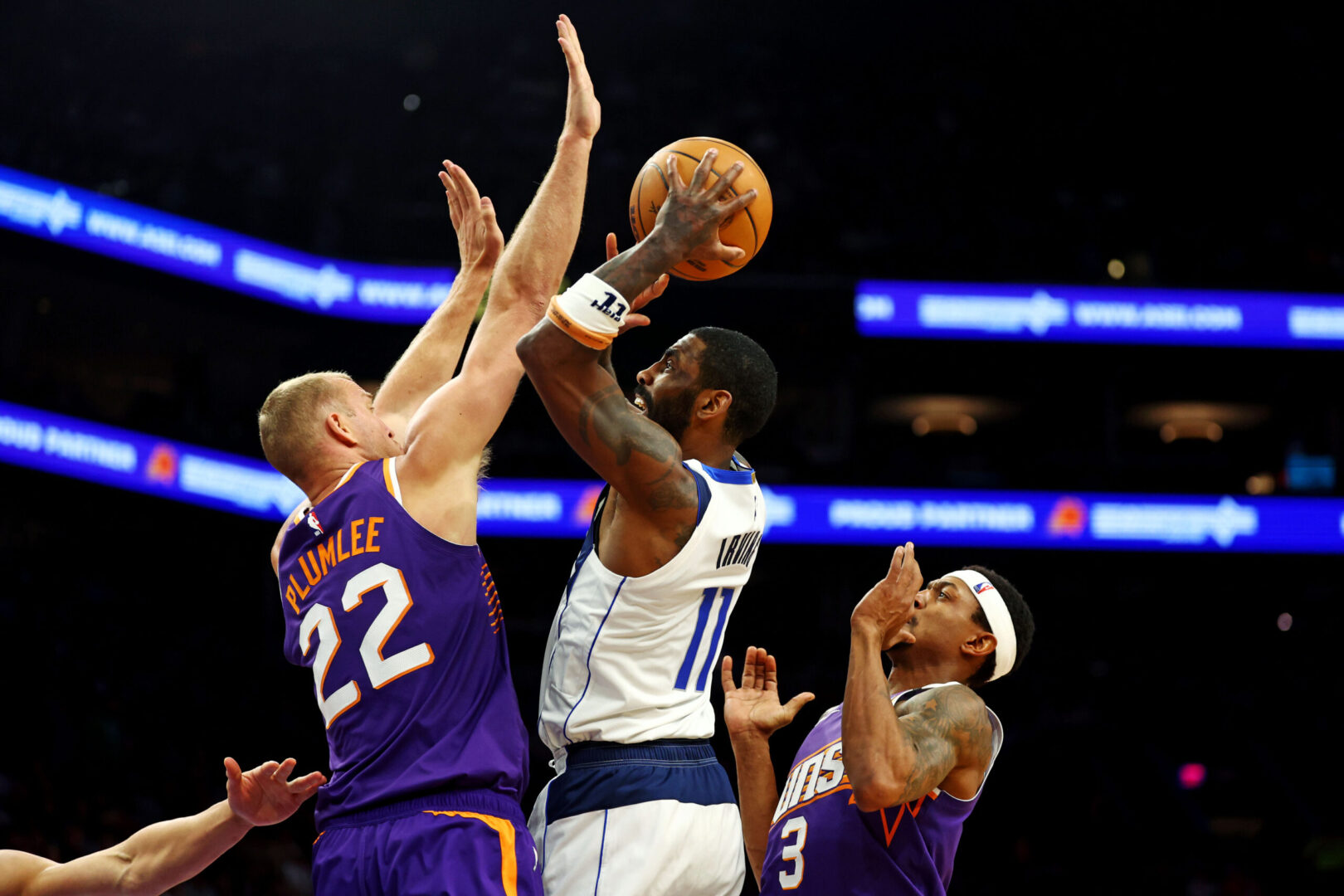 Dec 27, 2024; Phoenix, Arizona, USA; Dallas Mavericks guard Kyrie Irving (11) shoots the ball against Phoenix Suns center Mason Plumlee (22) and guard Bradley Beal (3) during the third quarter at Footprint Center. Mandatory Credit: Mark J. Rebilas-Imagn Images