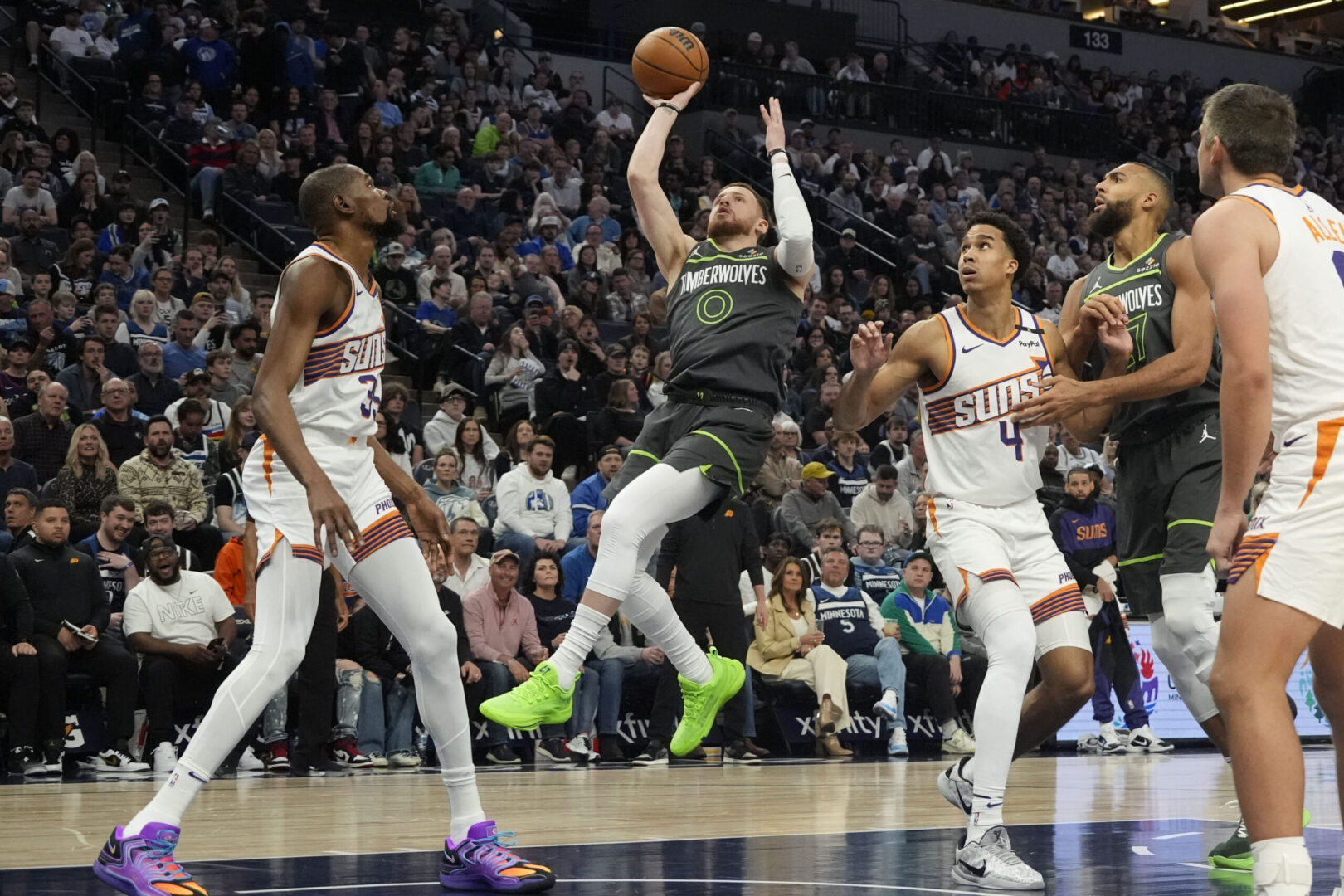 Mar 28, 2025; Minneapolis, Minnesota, USA; Minnesota Timberwolves guard Donte DiVincenzo (0) goes to the basket against Phoenix Suns forward Kevin Durant (35) and forward Oso Ighodaro (4) in the first quarter at Target Center. Mandatory Credit: Bruce Kluckhohn-Imagn Images