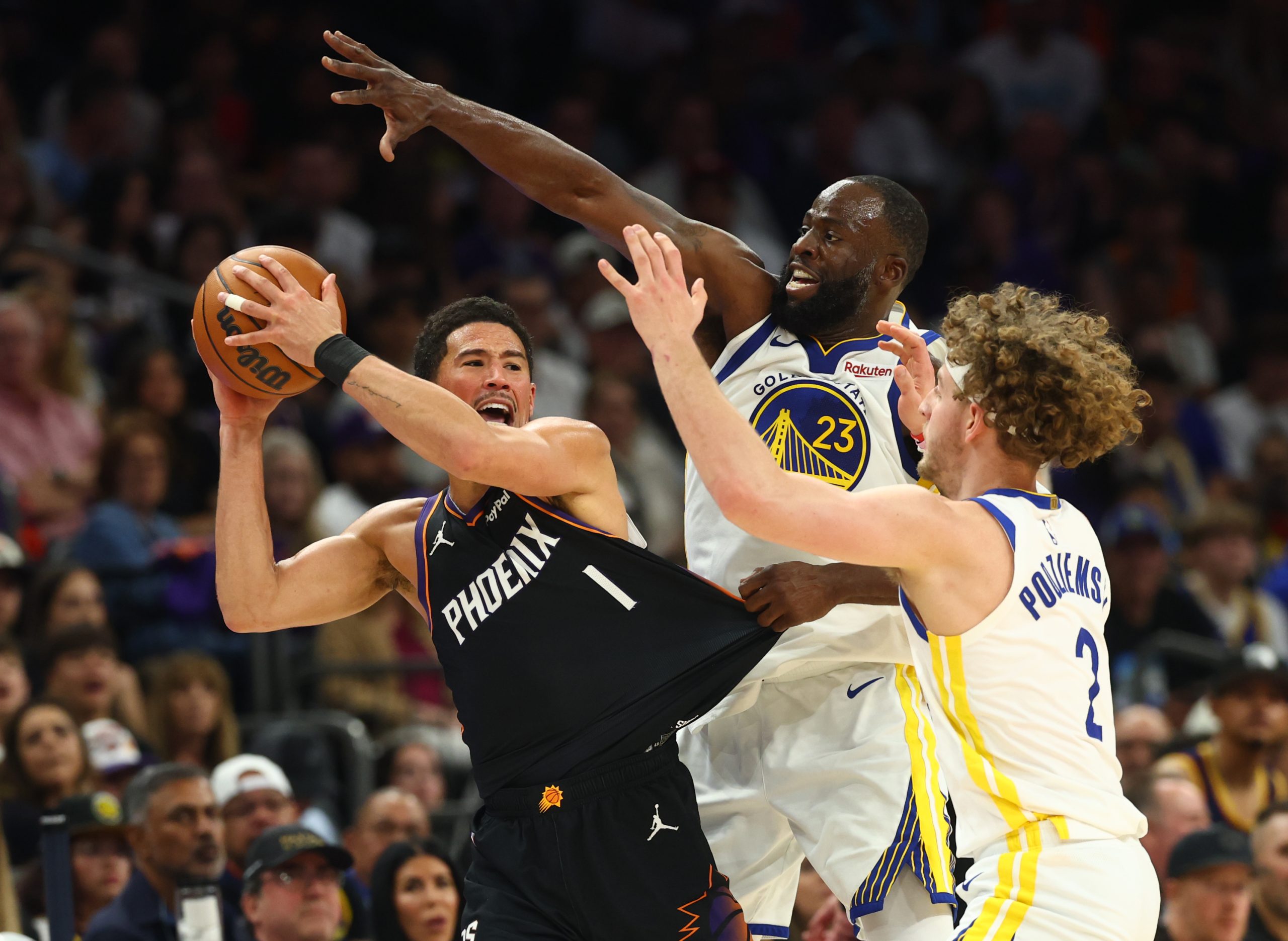 Apr 17, 2026; Phoenix, Arizona, USA; Phoenix Suns guard Devin Booker (1) looks to pass the ball against Golden State Warriors forward Draymond Green (23) and guard Brandin Podziemski (2) during the second half in the play-in rounds of the 2026 NBA Playoffs at Mortgage Matchup Center. Mandatory Credit: Mark J. Rebilas-Imagn Images